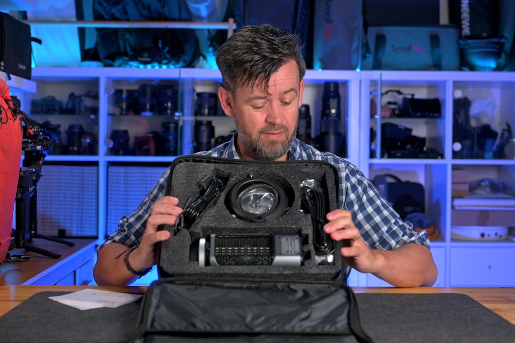 A man holding up what you get in the box with the Neewer MS150C video light.