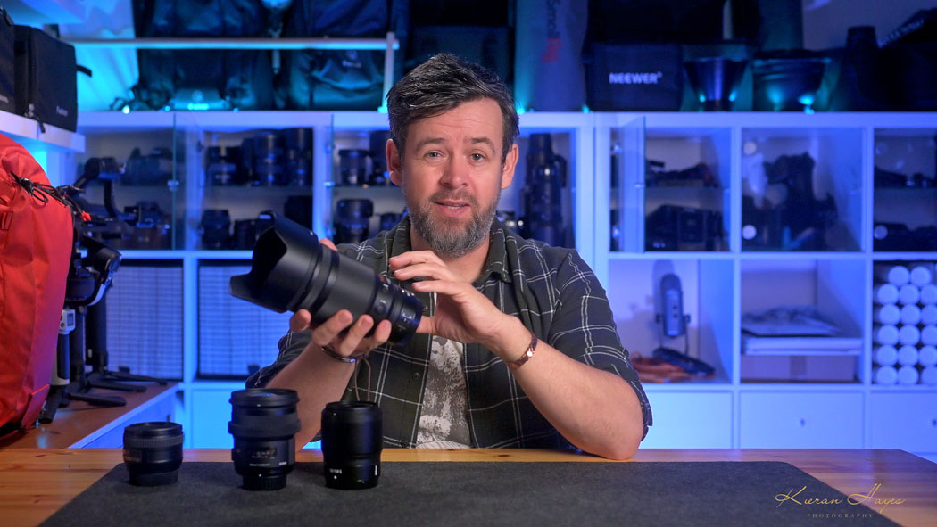 A man holding the Nikon Z 50mm F1.2 lens with three other 50mm lens for a group test of Nikon 50mm lenses