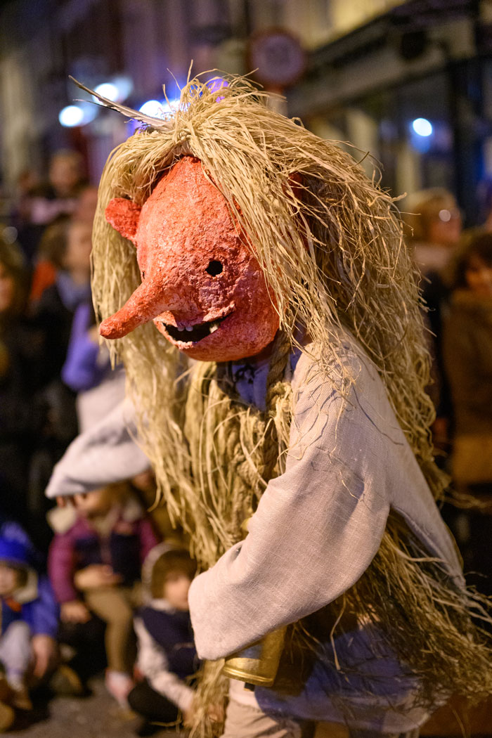 A street performer wearing a large mask during a parade.