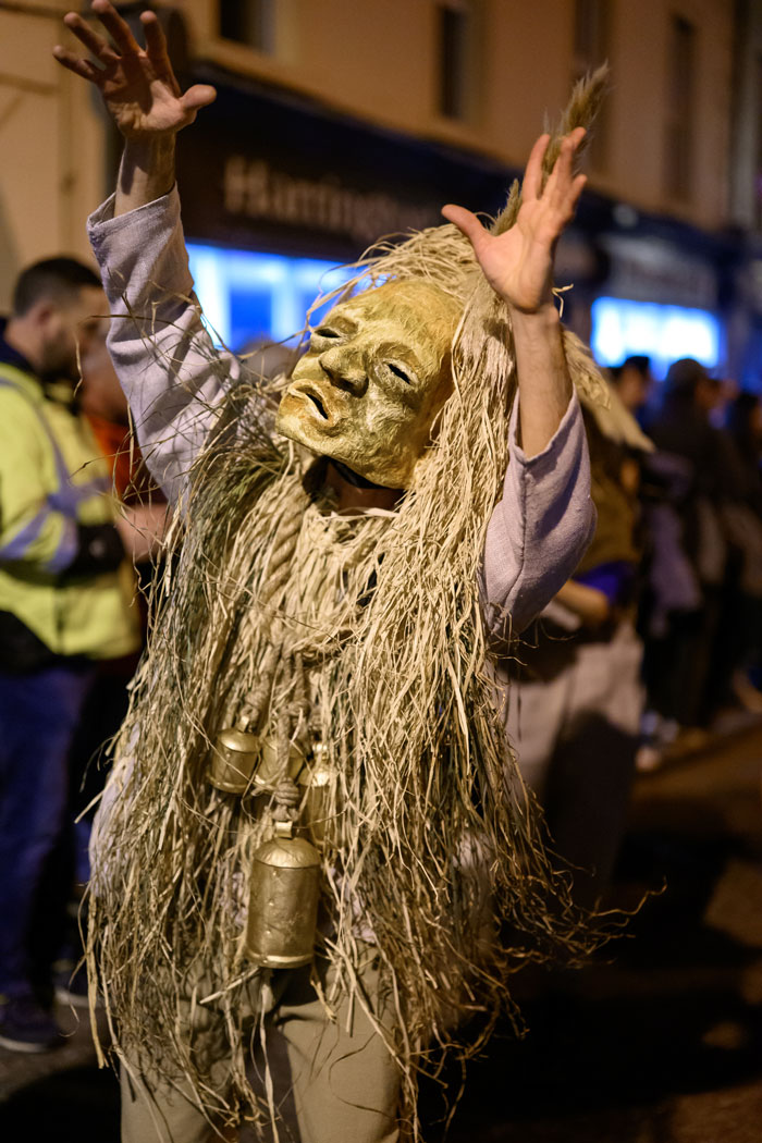 A street performer wearing a large mask during a parade.